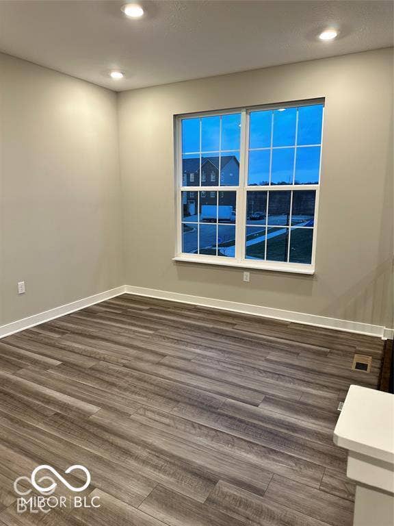 Neutral interior space featuring wood-finish flooring, recessed lighting, and a window with a grid pattern
