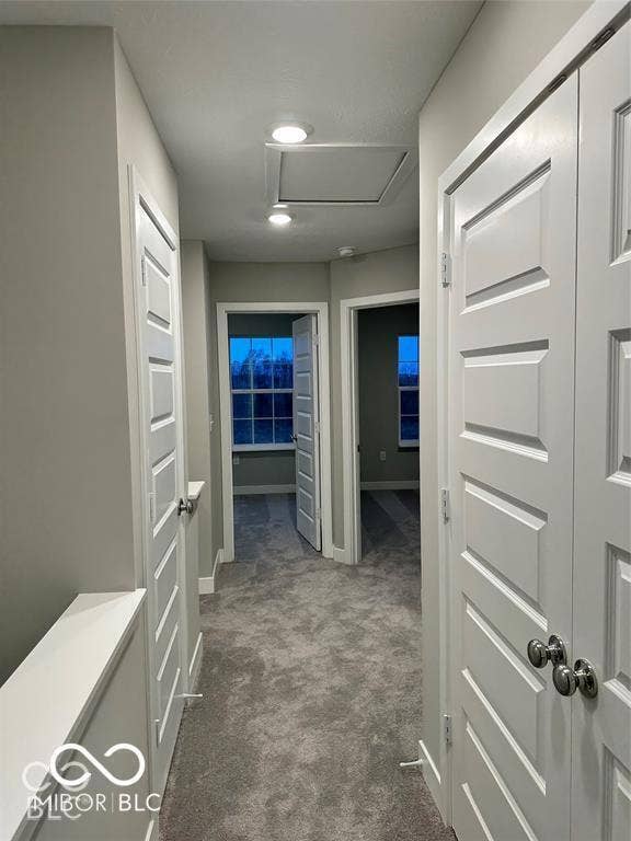 Hallway featuring grey carpeting, multi-panel interior doors with metallic hardware, and recessed lighting