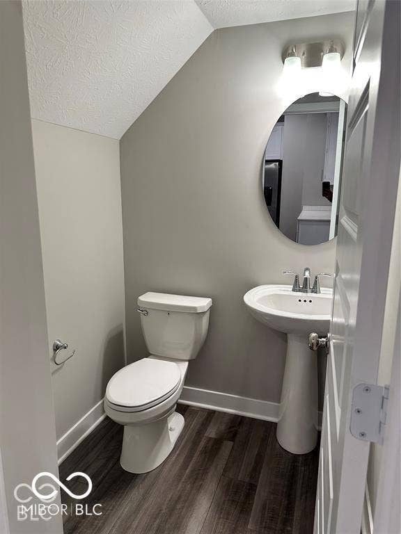 Pedestal sink with chrome faucet, oval wall-mounted mirror, wood-finish flooring, and two-light vanity fixture