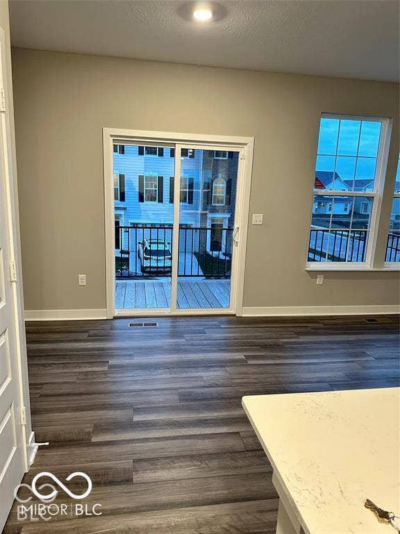 Wood-finish flooring, sliding glass door with balcony access, and multi-pane windows
