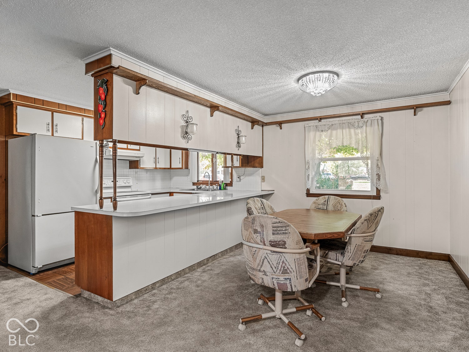 Kitchen featuring a breakfast bar, white cabinetry, wood-trim detailing, and a flush-mount ceiling light