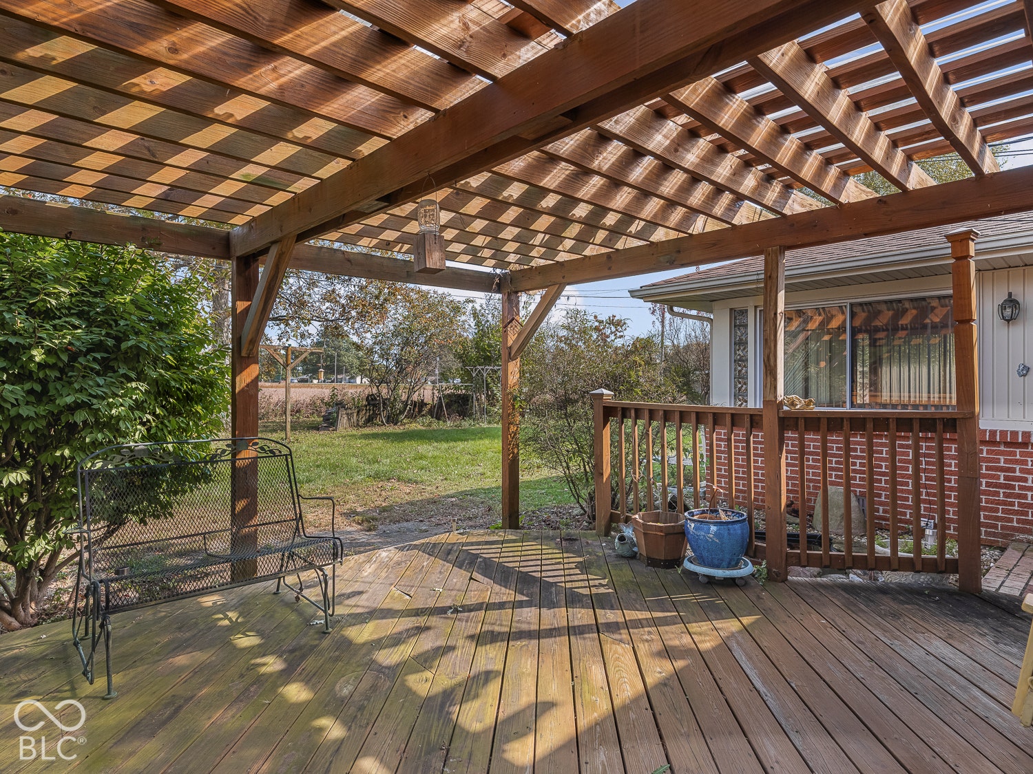 Wood-decked patio featuring a timber pergola, wood railing, and brick exterior cladding