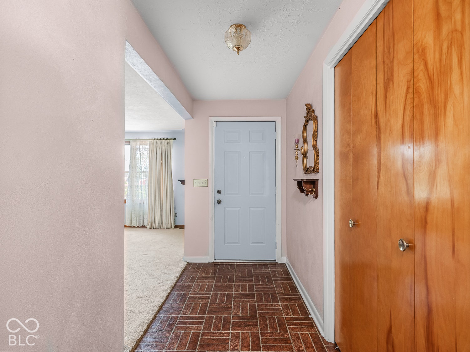 Entryway featuring tile flooring, six-panel solid-core door, and wood-finish closet doors with polished hardware