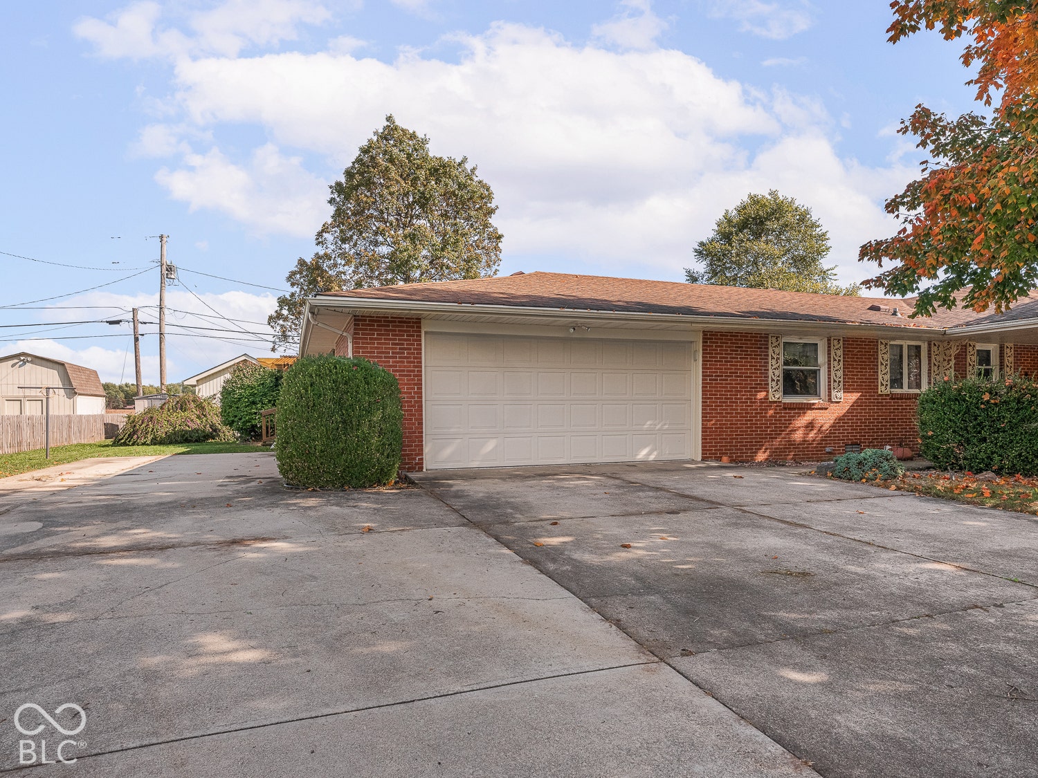 Red brick exterior featuring a multi-car concrete driveway and an oversized two-car attached garage with a paneled door