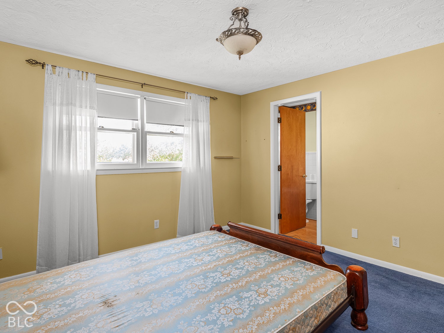 Multi-pane windows, brass-finish curtain hardware, ceiling light fixture, and an en suite bathroom