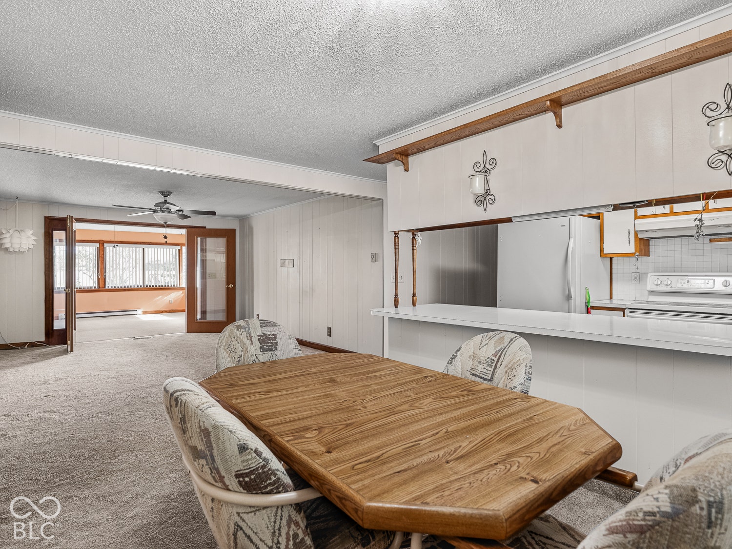 Kitchen featuring a pass-through breakfast bar, built-in cabinetry with decorative accents, and overhead display shelving