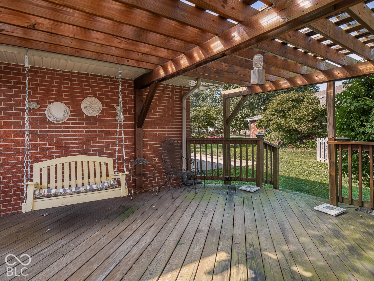 Covered wooden deck featuring a natural wood pergola, red brick exterior wall, and wood-finish decking