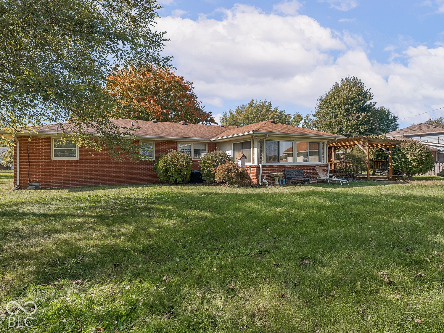 Red brick exterior with an attached wooden pergola and expansive lawn