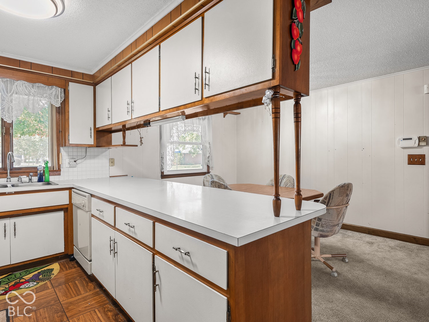 Kitchen featuring wood cabinetry with white panels, a peninsula countertop, parquet flooring, and dual-basin sink.