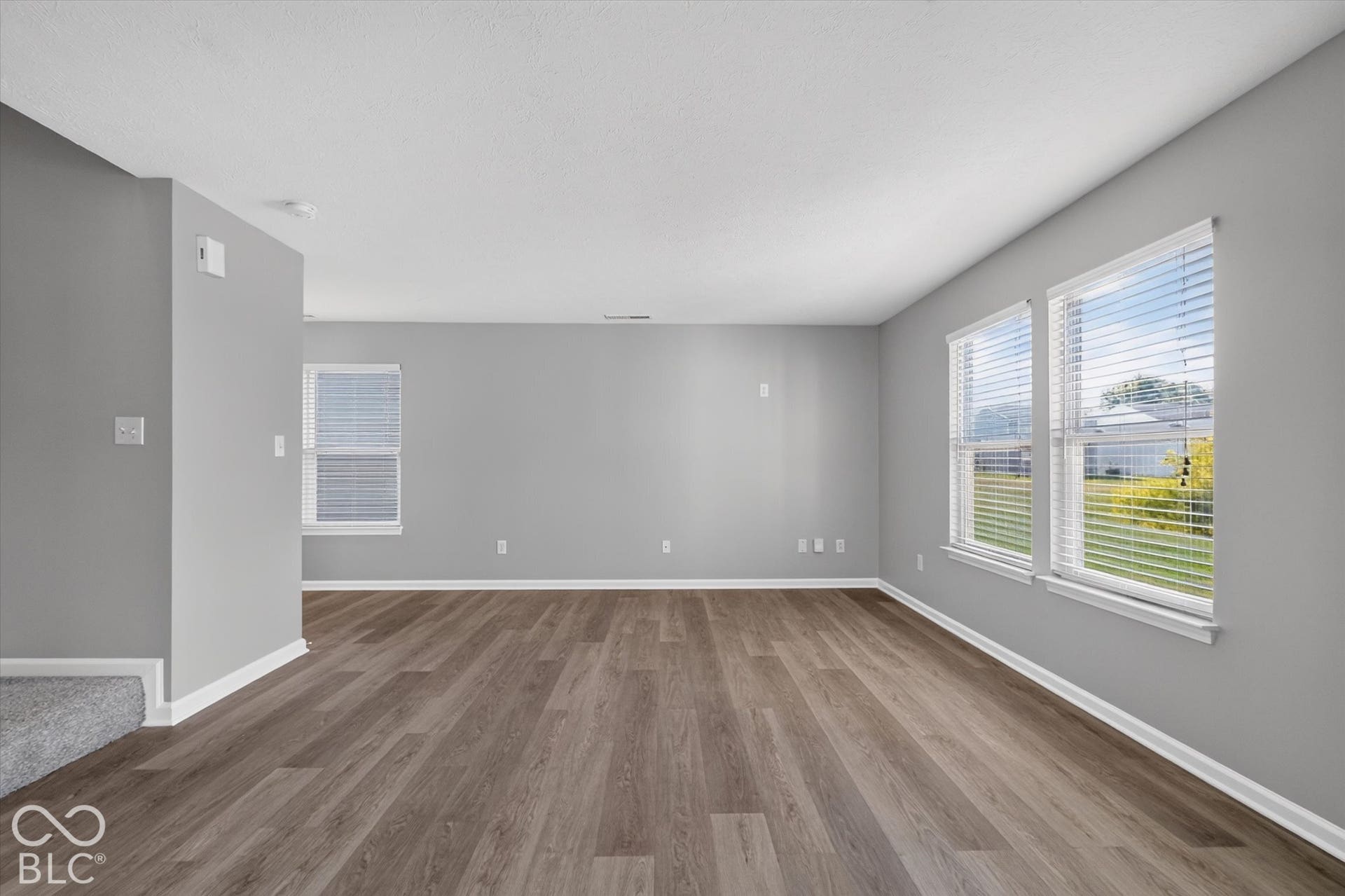 Spacious, open-concept living room with newer LVP flooring and neutral wall color