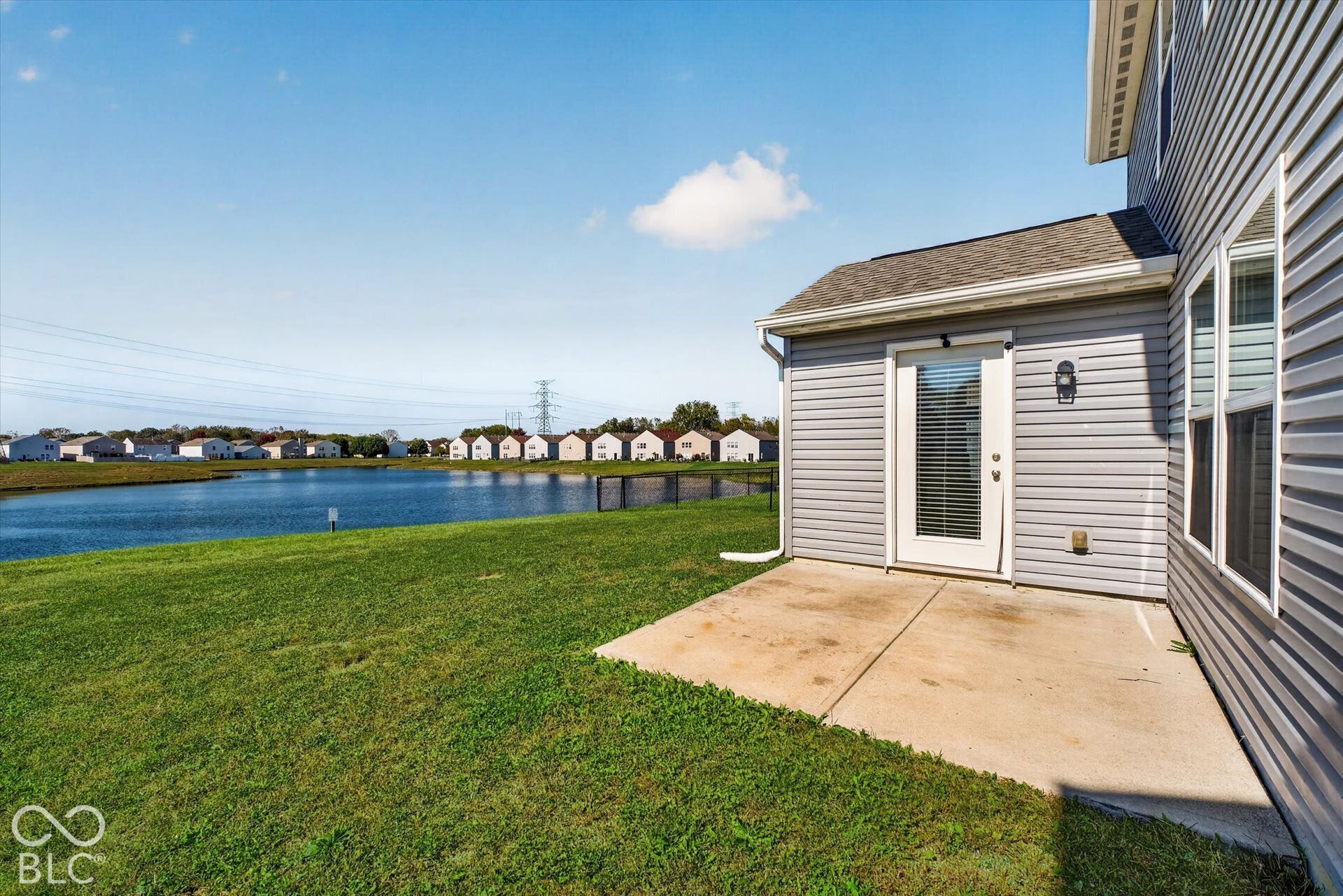 View of backyard featuring a concrete patio and pond view