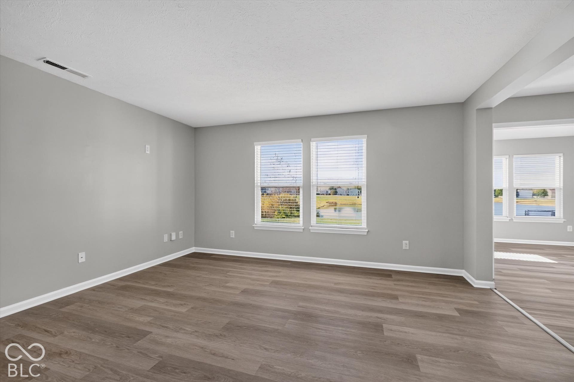 Spacious, open-concept living room with newer LVP flooring and neutral wall color