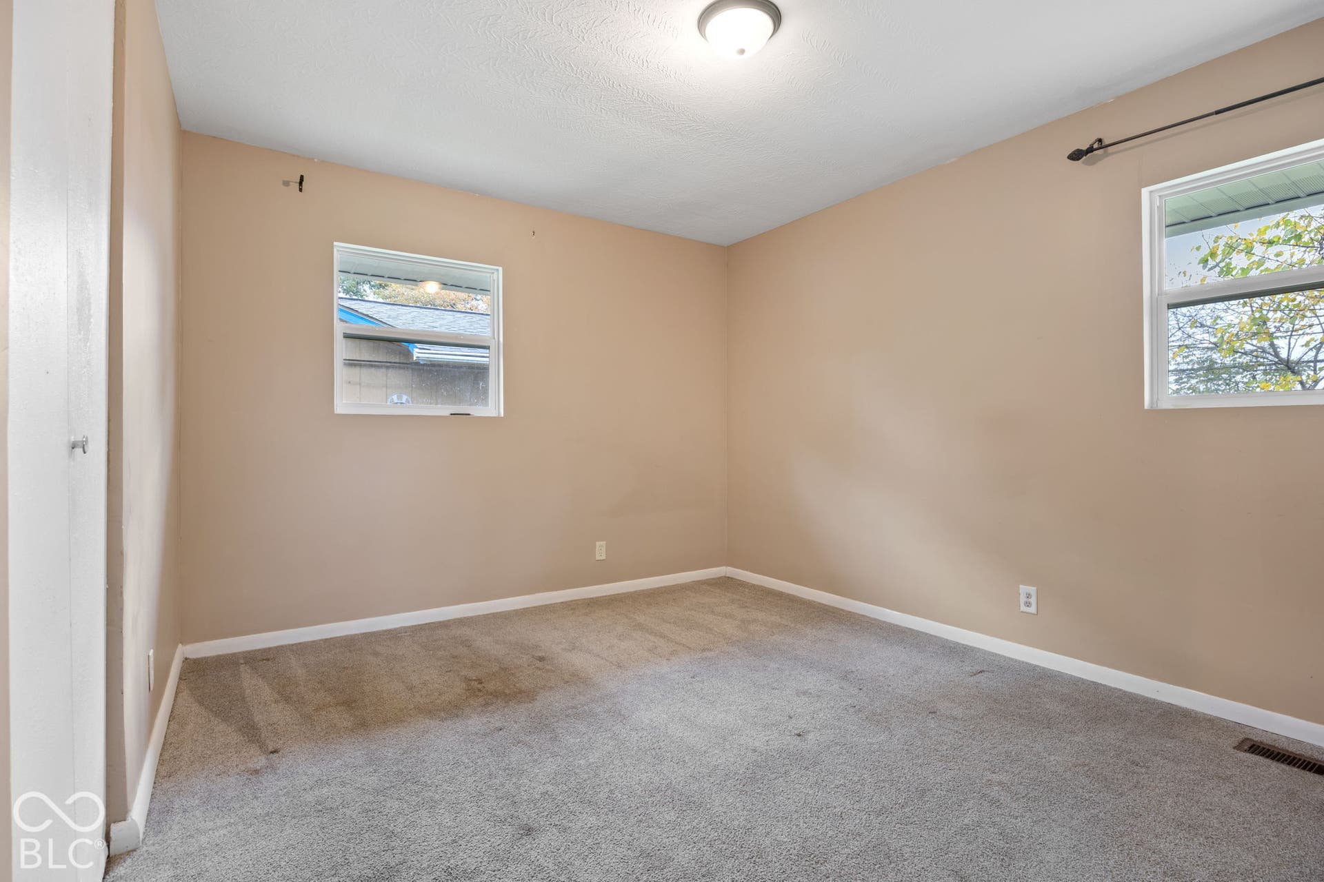 3721 Ireland Drive, Indianapolis, IN 46235 Neutral-toned interior space featuring wall-to-wall carpeting, two dual-pane windows, and a flush-mount ceiling light fixture