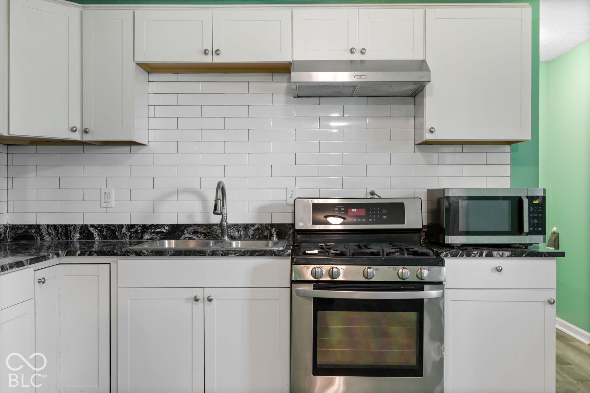 3721 Ireland Drive, Indianapolis, IN 46235 Kitchen featuring white Shaker-style cabinetry, dark patterned stone countertops, a white subway tile backsplash, stainless steel gas range, and stainless steel range hood