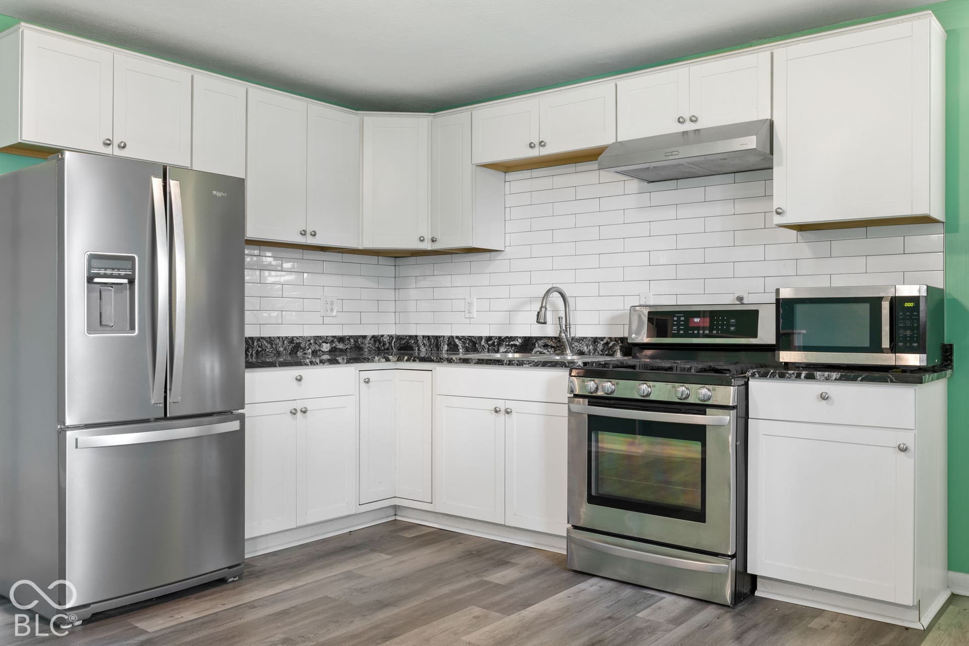 3721 Ireland Drive, Indianapolis, IN 46235 Kitchen featuring white shaker-style cabinetry, dark stone countertops, white subway tile backsplash, stainless steel appliances, and wood-finish flooring