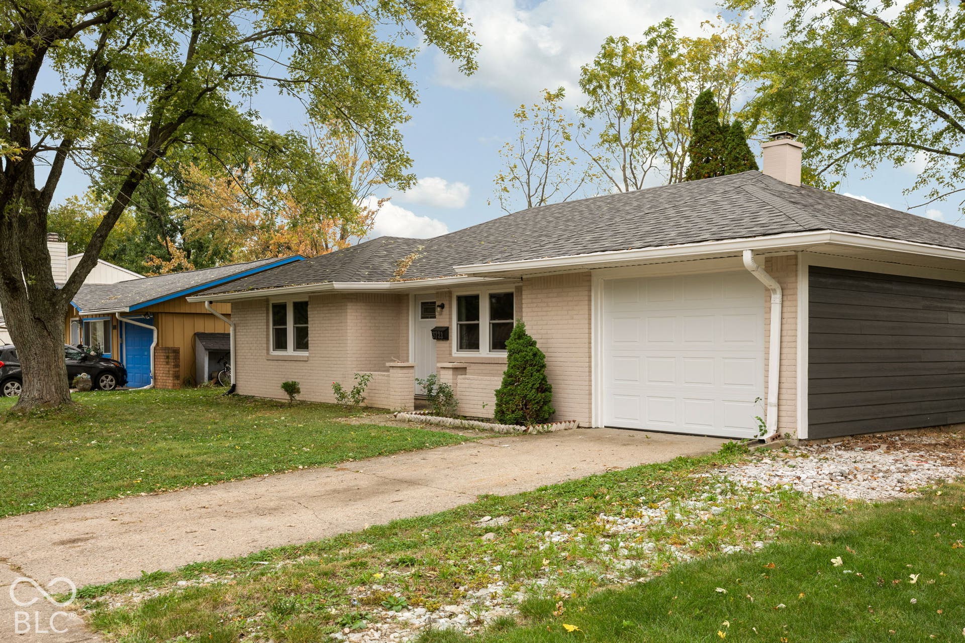 3721 Ireland Drive, Indianapolis, IN 46235 Single-story residence featuring light-toned brick exterior, asphalt shingle roof, attached garage with charcoal-finish door, and concrete driveway