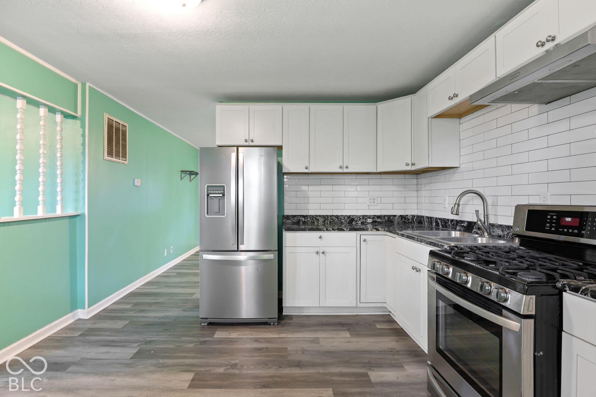 3721 Ireland Drive, Indianapolis, IN 46235 Kitchen featuring white shaker-style cabinetry, dark stone-patterned countertops, a white subway tile backsplash, stainless steel appliances, and wood-finish flooring