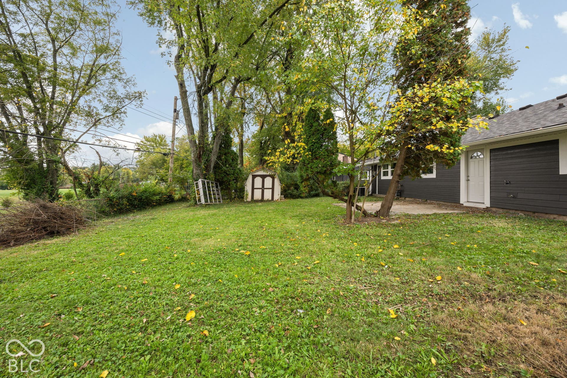 3721 Ireland Drive, Indianapolis, IN 46235 Backyard featuring a grass lawn, mature trees, a concrete patio, and a detached storage structure