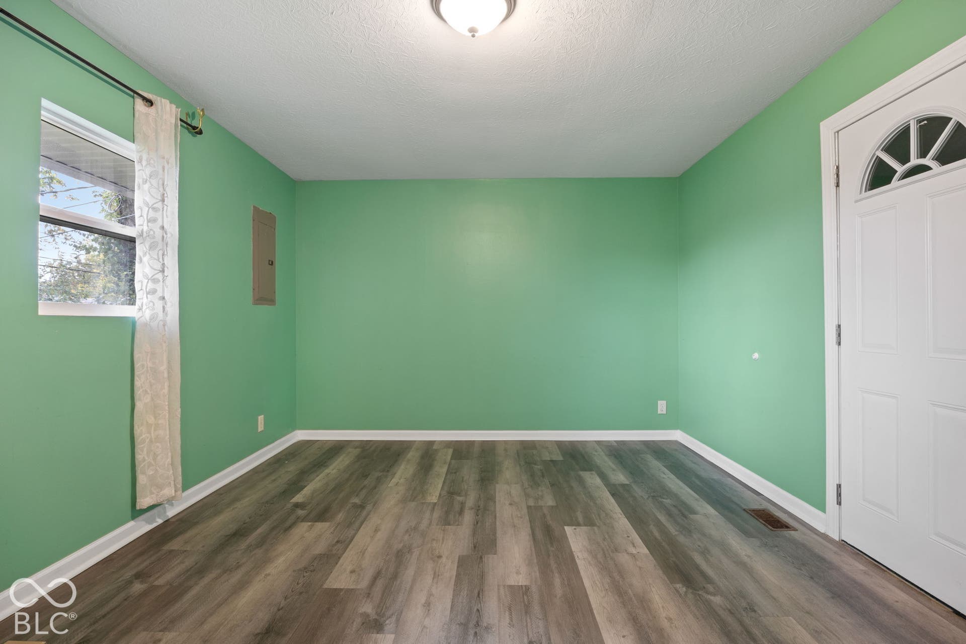 3721 Ireland Drive, Indianapolis, IN 46235 Wood-finish flooring, white door with arched glass inlay, flush-mount ceiling lighting, and single-pane window