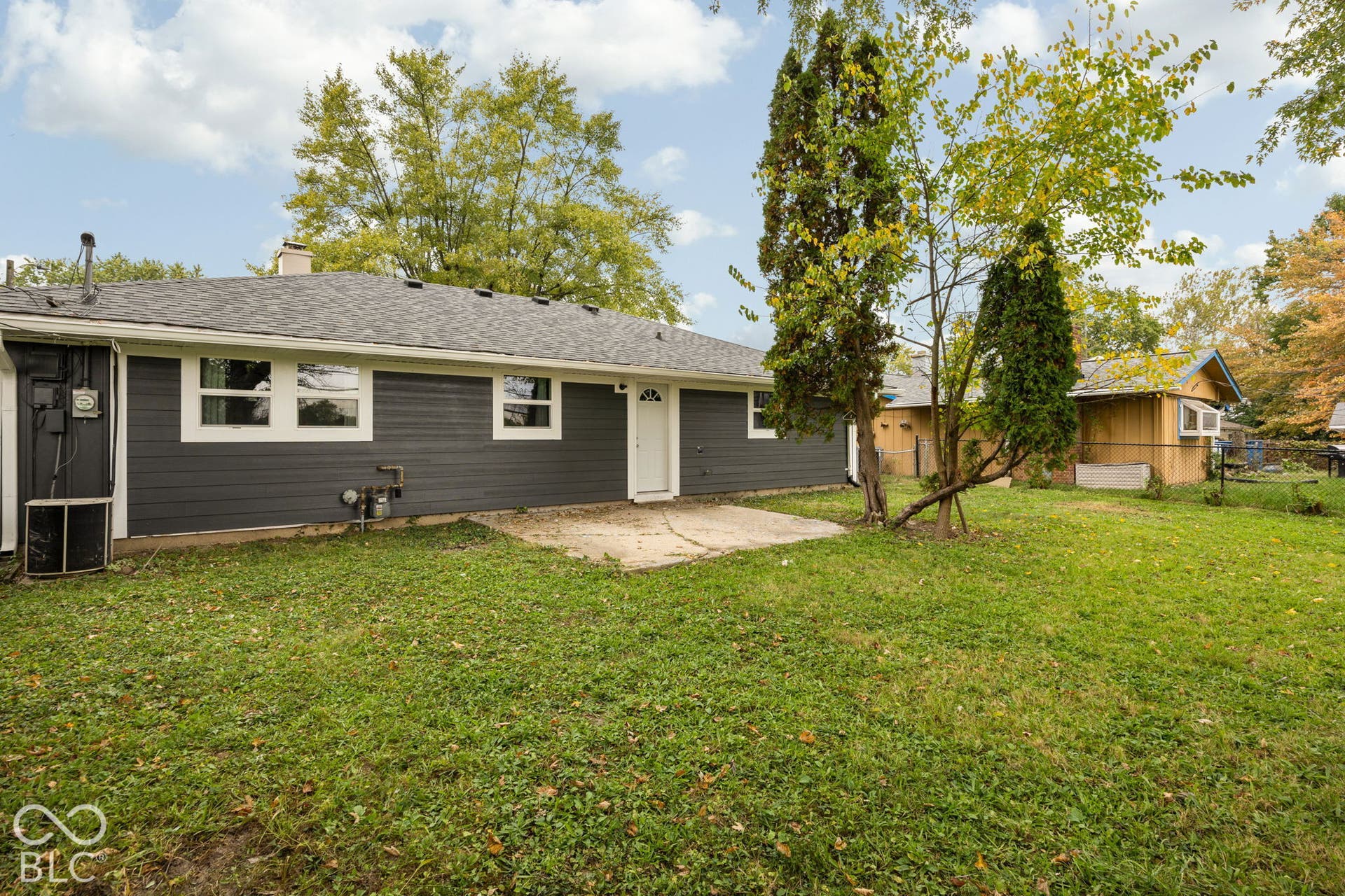 3721 Ireland Drive, Indianapolis, IN 46235 Exterior featuring dark horizontal siding, a concrete patio, and mature trees
