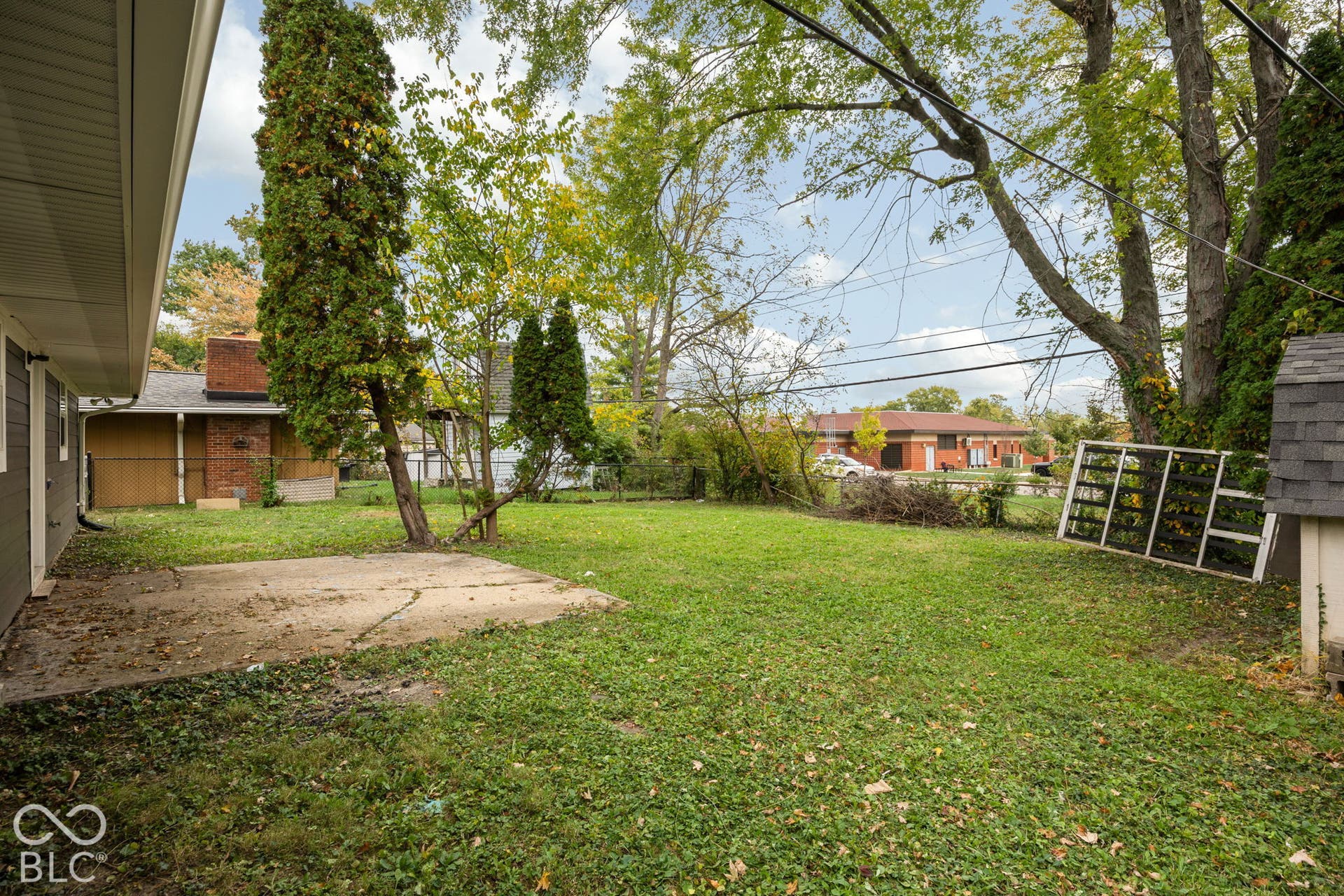 3721 Ireland Drive, Indianapolis, IN 46235 Backyard area featuring a concrete patio, mature trees, and perimeter fencing