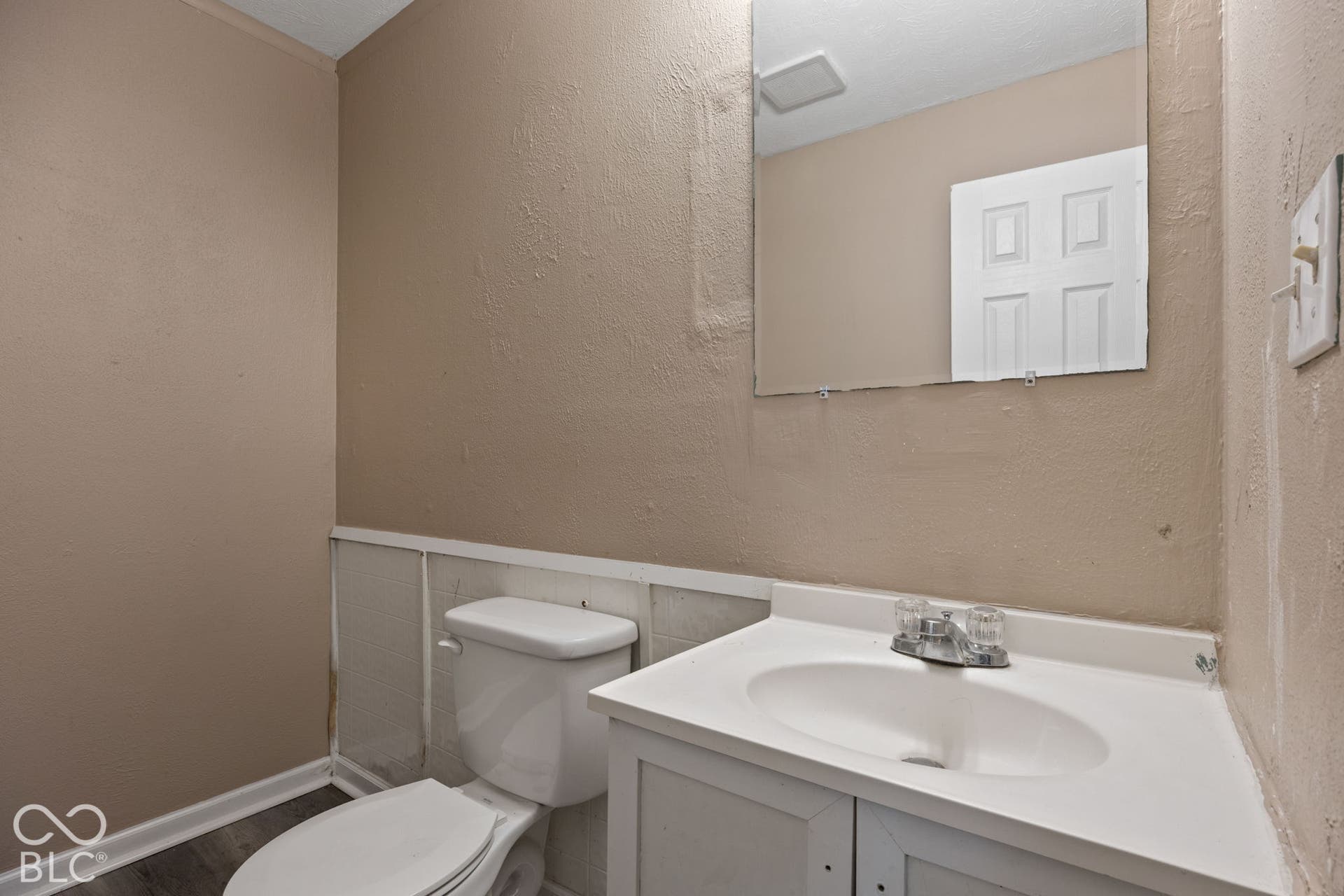 3721 Ireland Drive, Indianapolis, IN 46235 Single-basin vanity with integrated countertop and chrome-finish dual-handle faucet, wall-mounted mirror, and standard porcelain commode