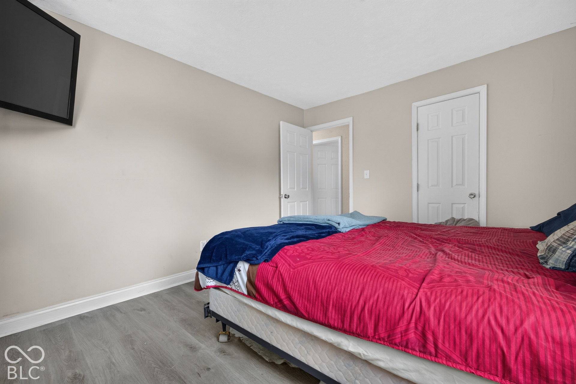 Neutral wall paint, wood-finish flooring, and white interior doors with six-panel detailing
