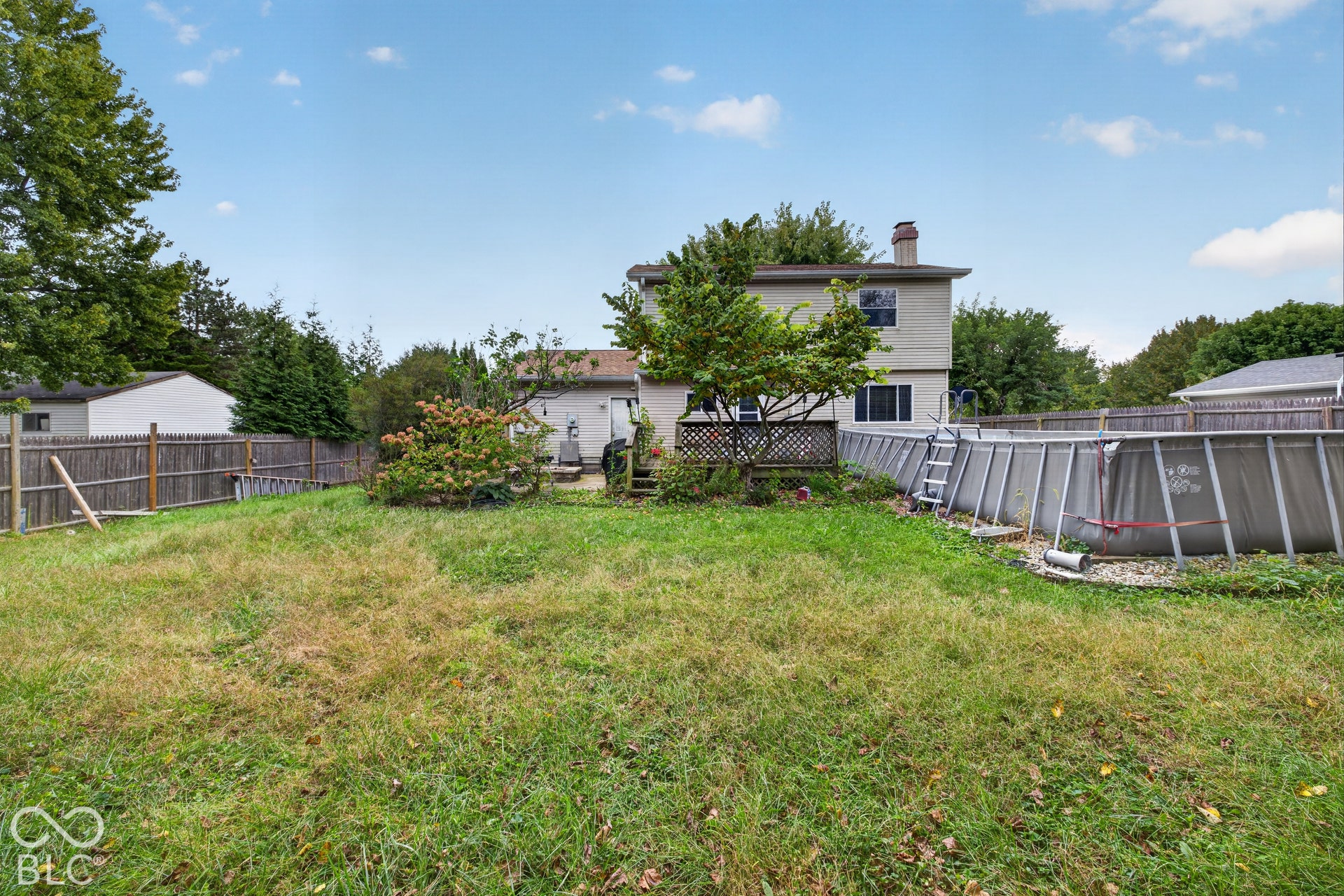 Rear exterior featuring a wood deck, fenced perimeter, and established landscaping