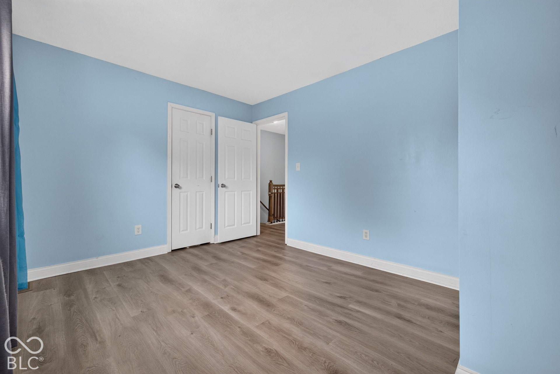 Interior room featuring wood-finish flooring, two six-panel doors, and neutral wall paint