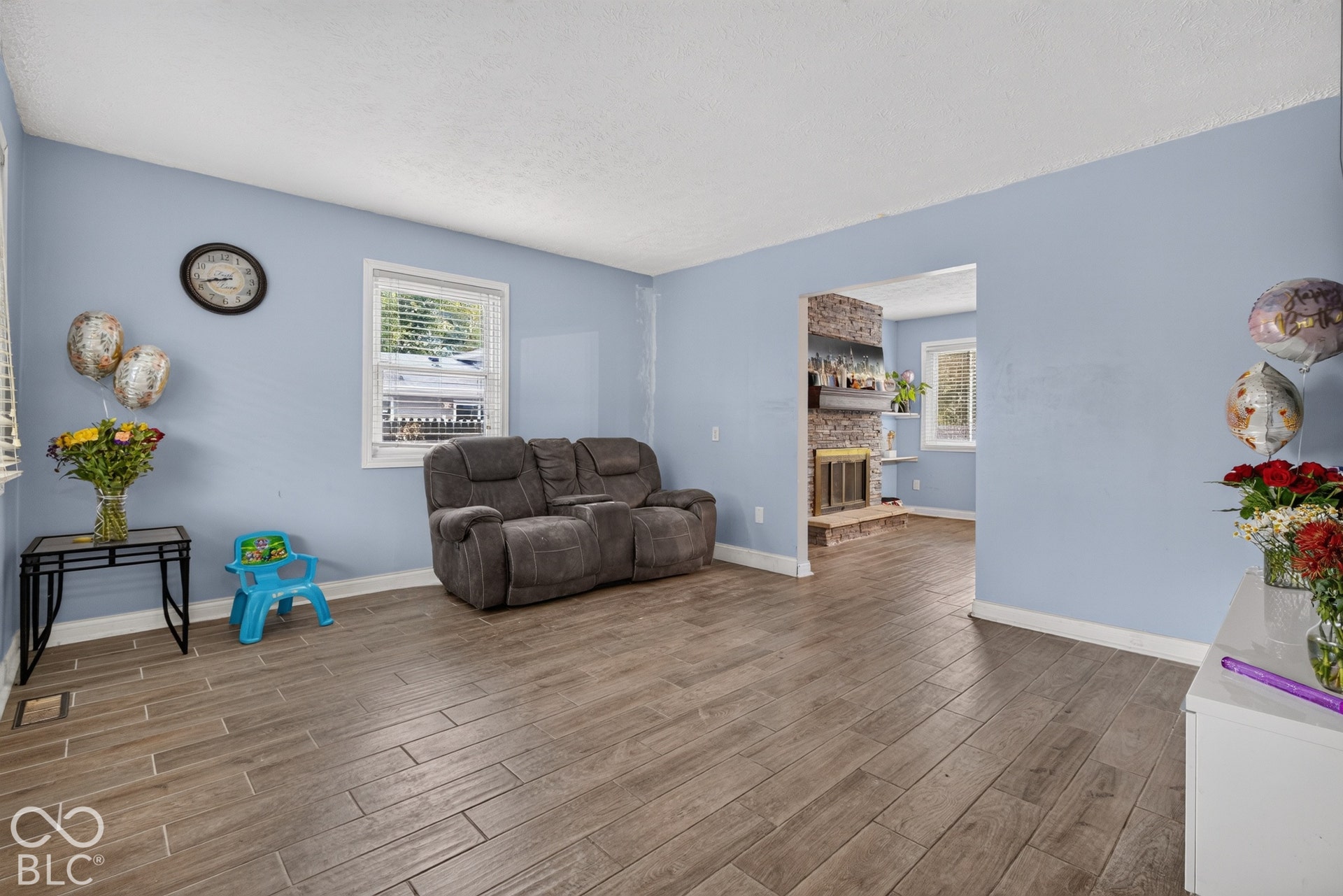 Wood-finish tile flooring, textured ceilings, and a brick fireplace featuring a wood mantel