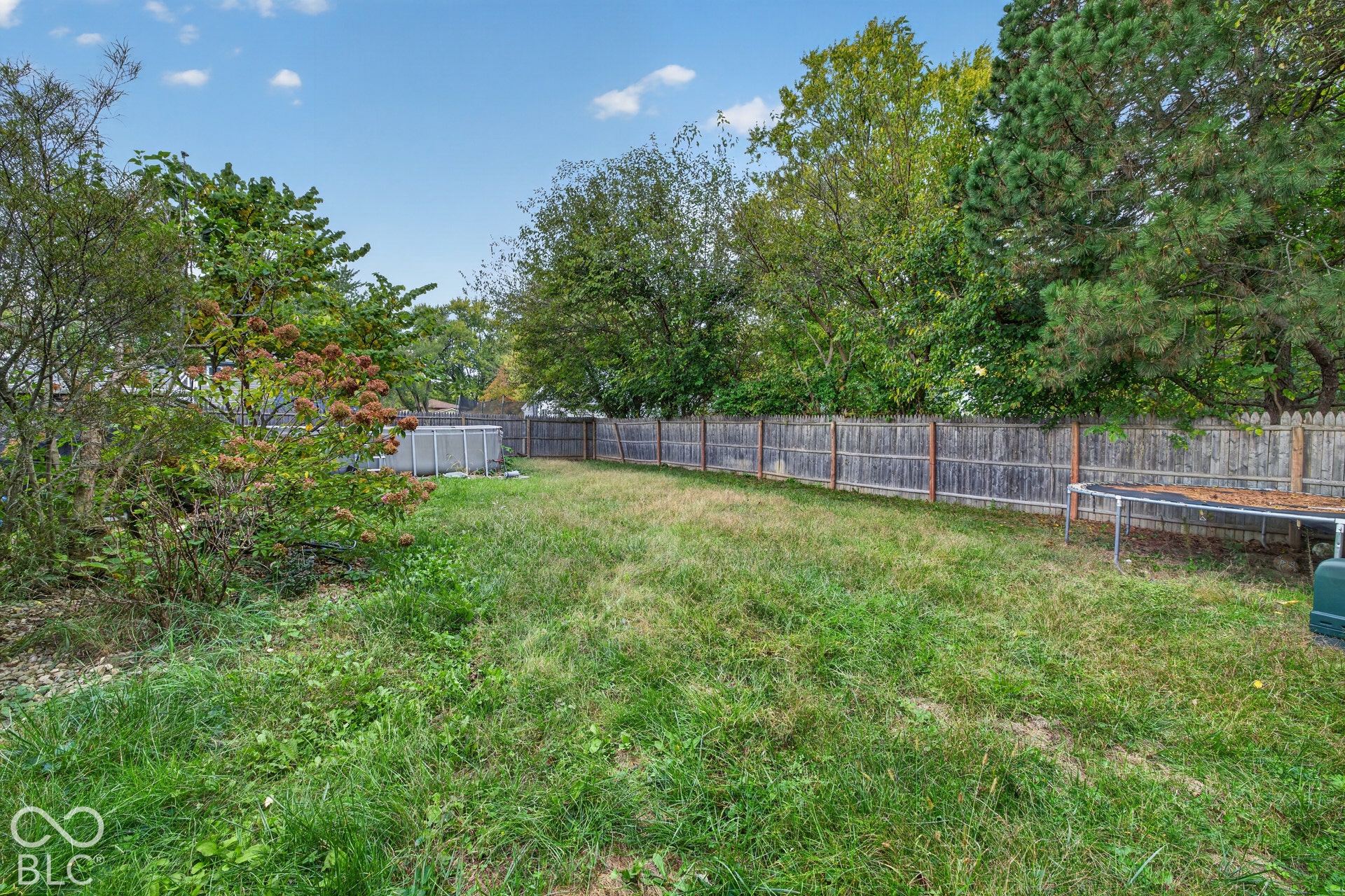Spacious backyard featuring a wood privacy fence and mature perimeter trees