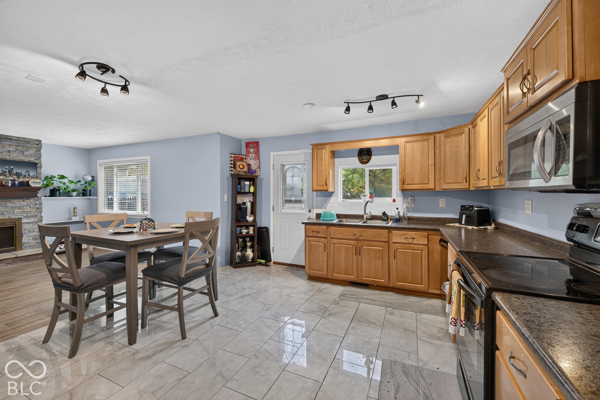 Kitchen featuring wood cabinetry, stone-texture countertops, tile flooring, and stainless steel microwave