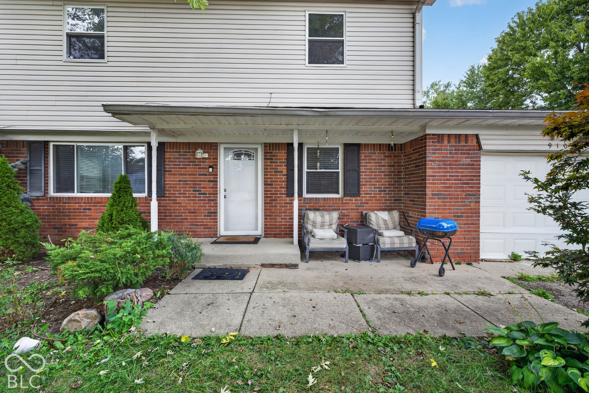Two-story residence featuring a brick and horizontal siding exterior, a covered concrete front porch, and a single-car garage