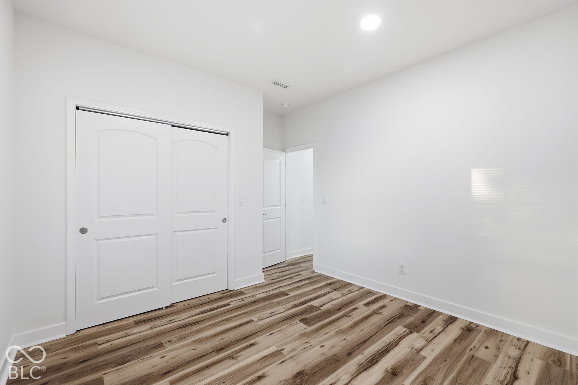 Neutral interior space featuring wood-finish flooring, recessed lighting, and a closet with two-panel sliding doors
