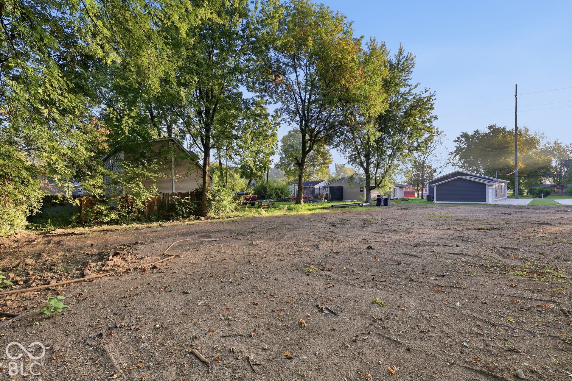 Expansive open lot featuring mature trees, a detached garage, and an open earth terrain