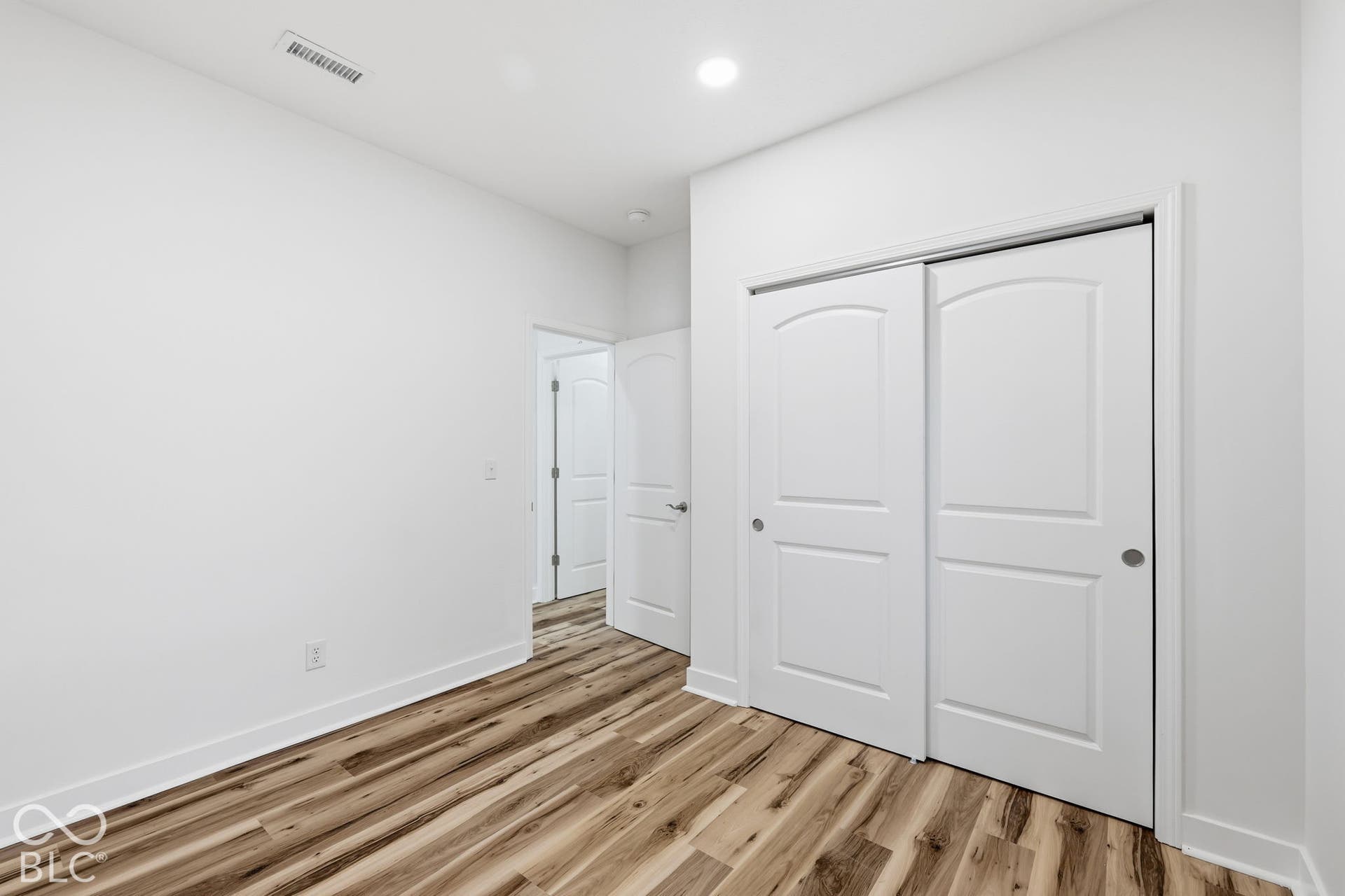Room featuring wood-finish flooring, recessed lighting, and a sliding-door closet with a two-panel design