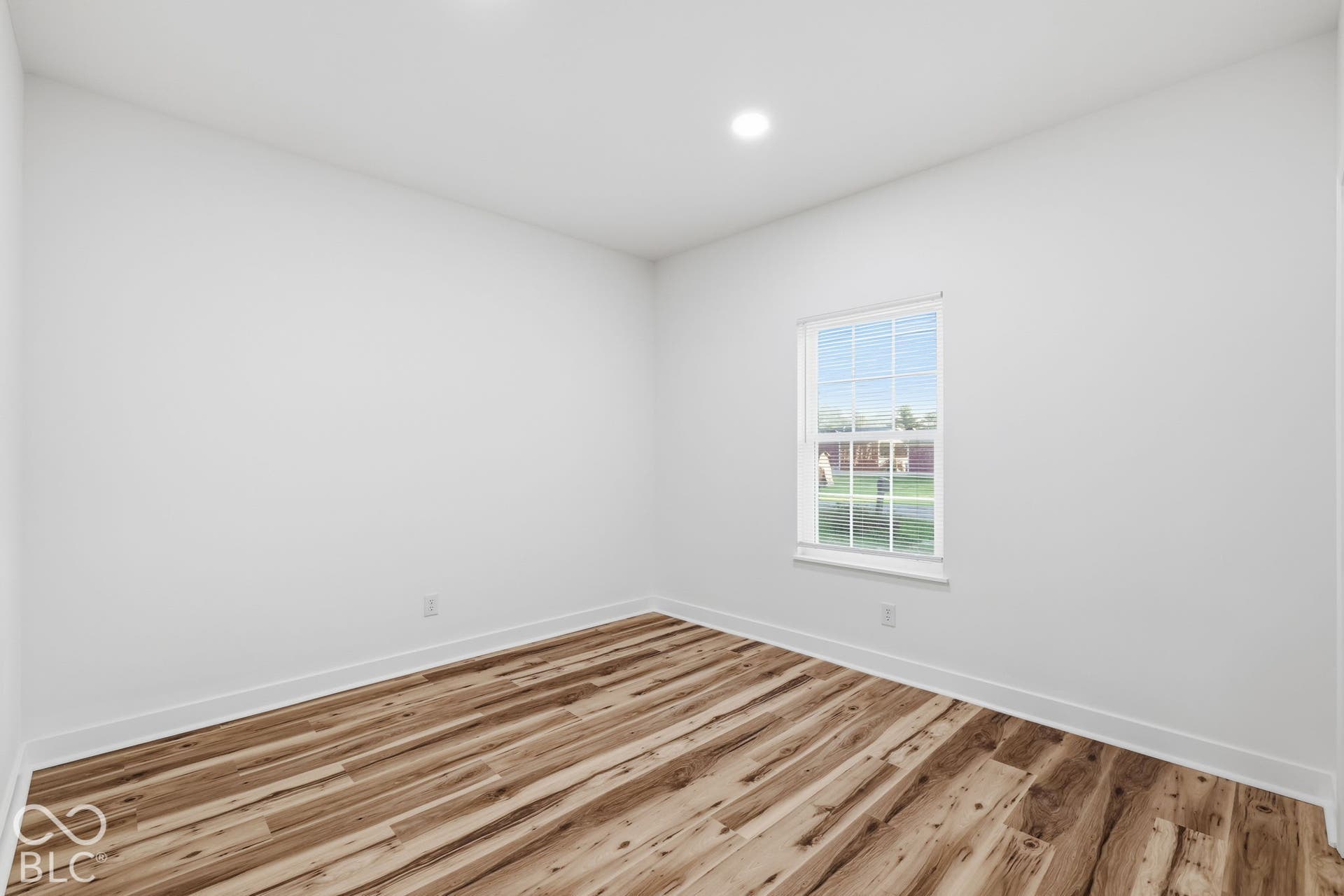 Neutral-toned room featuring wood-finish flooring, recessed lighting, and a single-hung window with muntins