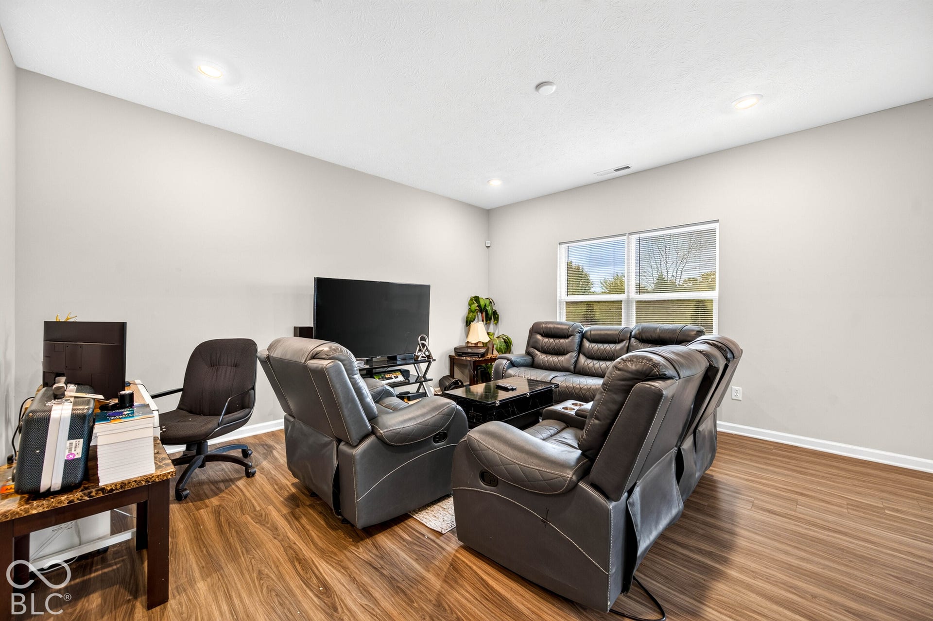 Room featuring wood-finish flooring, neutral wall paint, recessed lighting, and large windows