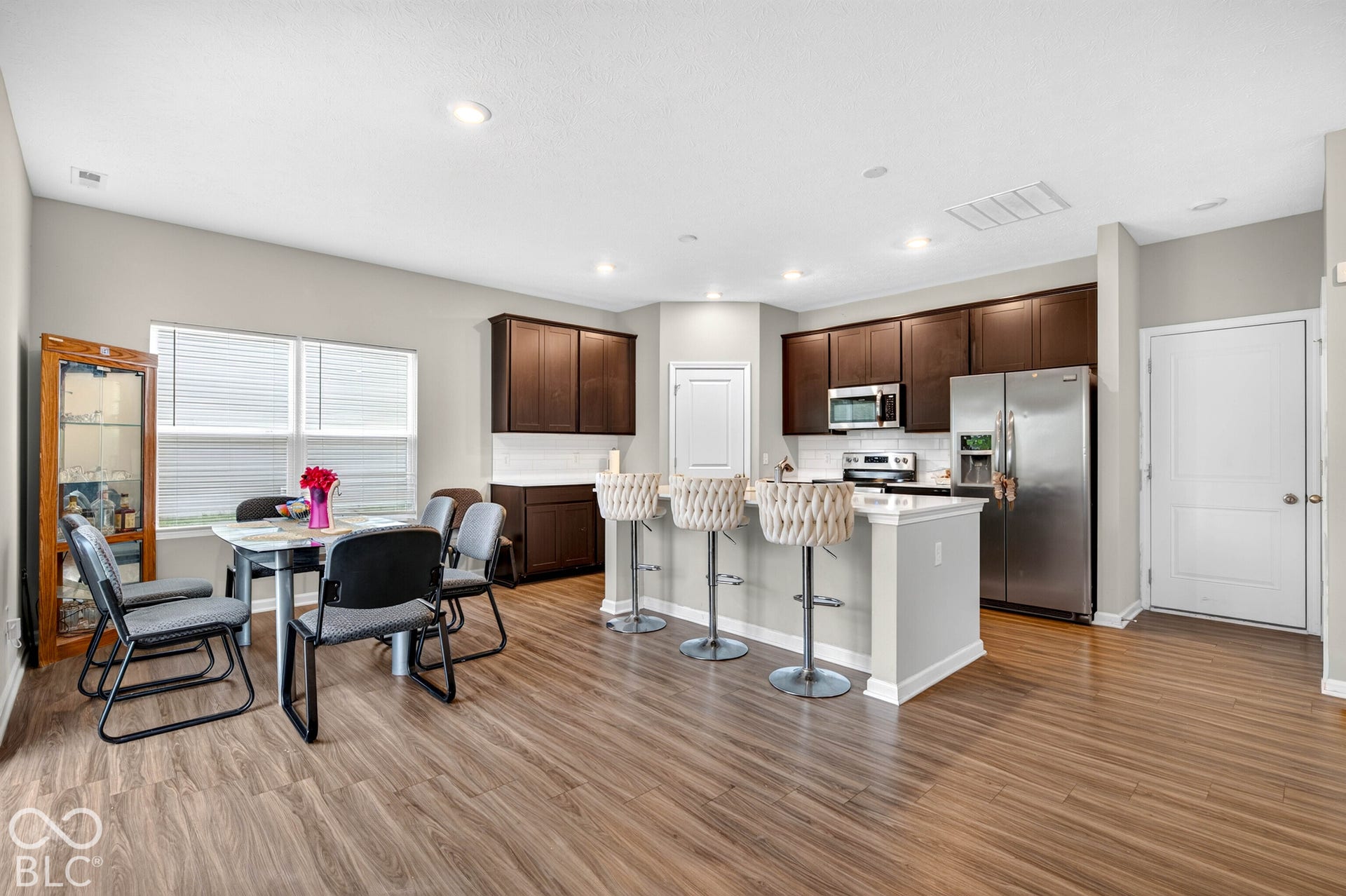 Kitchen featuring dark wood cabinetry, stainless steel appliances, a center island with a stone-finish countertop, and wood-finish flooring