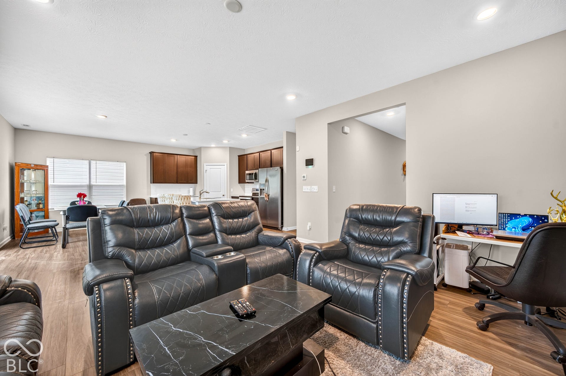 Open-concept interior featuring wood-finish flooring, recessed lighting, and kitchen cabinetry with stainless steel appliances