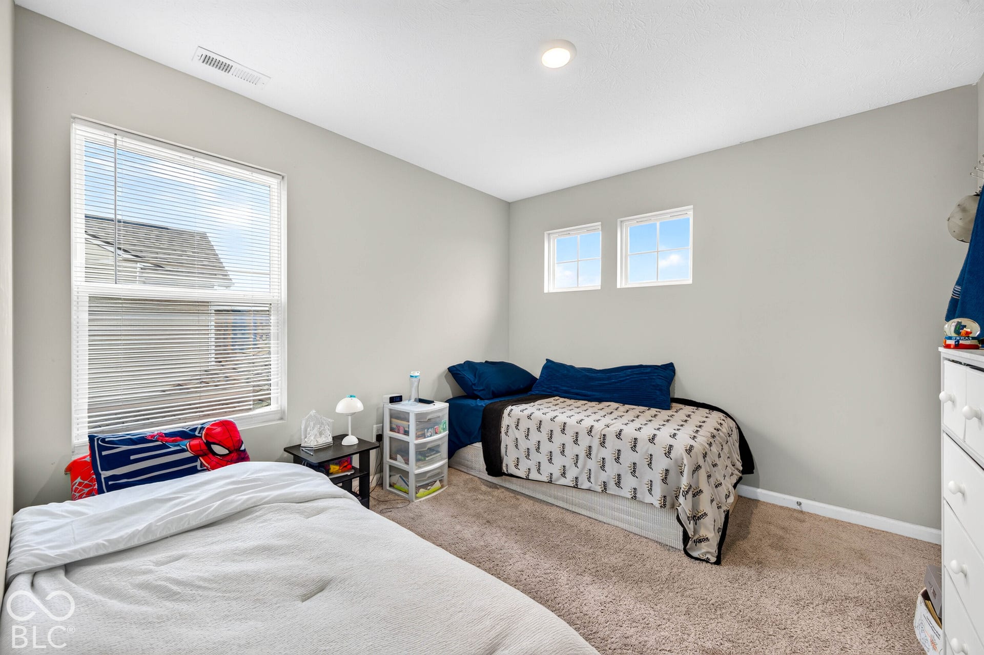 Neutral-toned room featuring wall-to-wall carpeting, one large double-hung window, and two fixed upper-level windows providing natural light