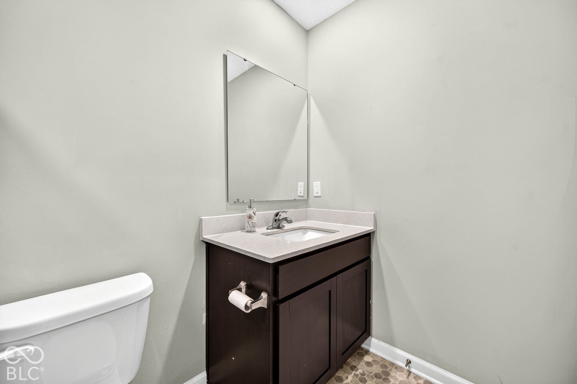 Dark-finish vanity featuring a stone-surface countertop, rectangular undermount sink, single-handle metal faucet, and wall-mounted mirror