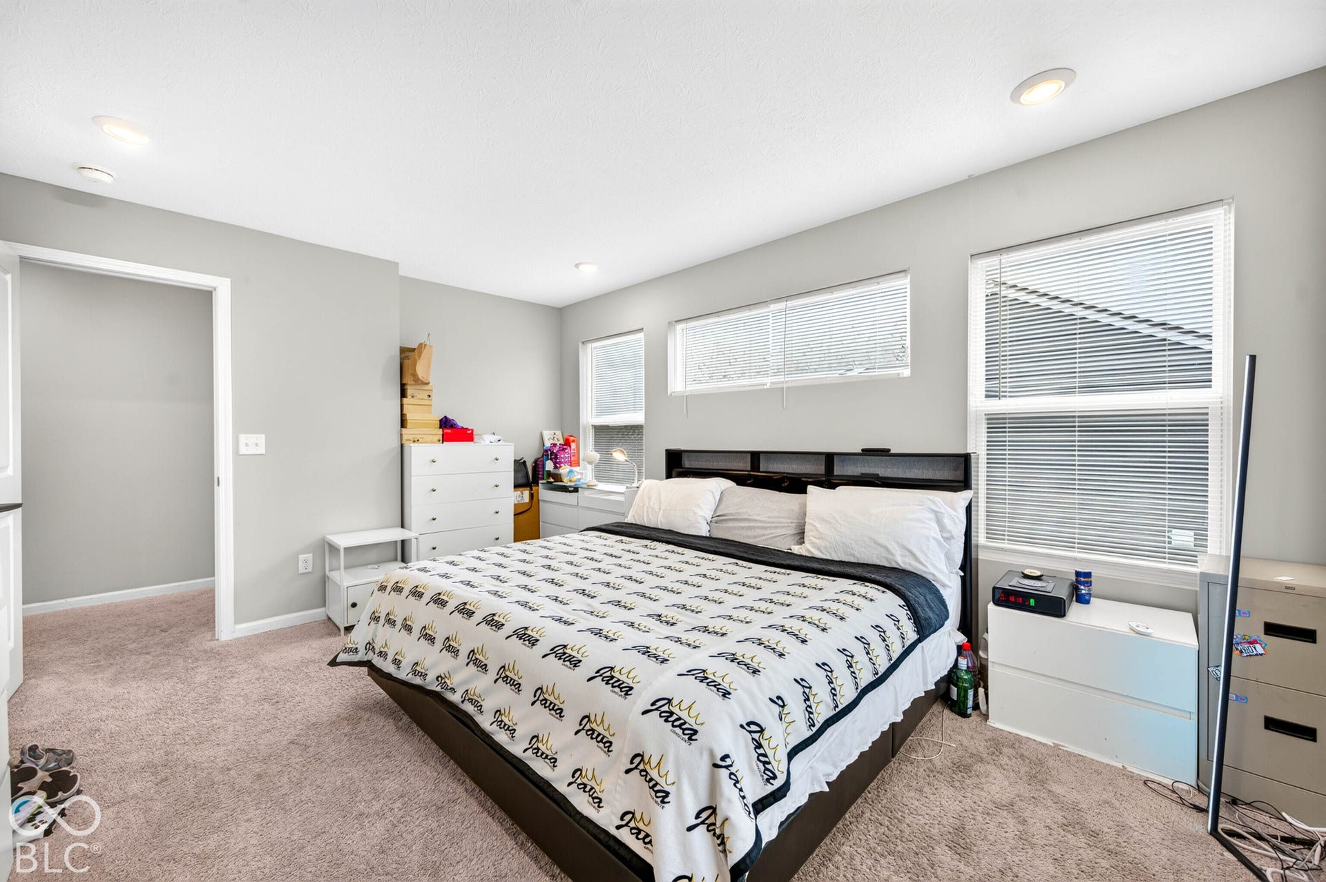 Neutral-toned carpeted flooring, recessed lighting, and multiple windows with horizontal blinds