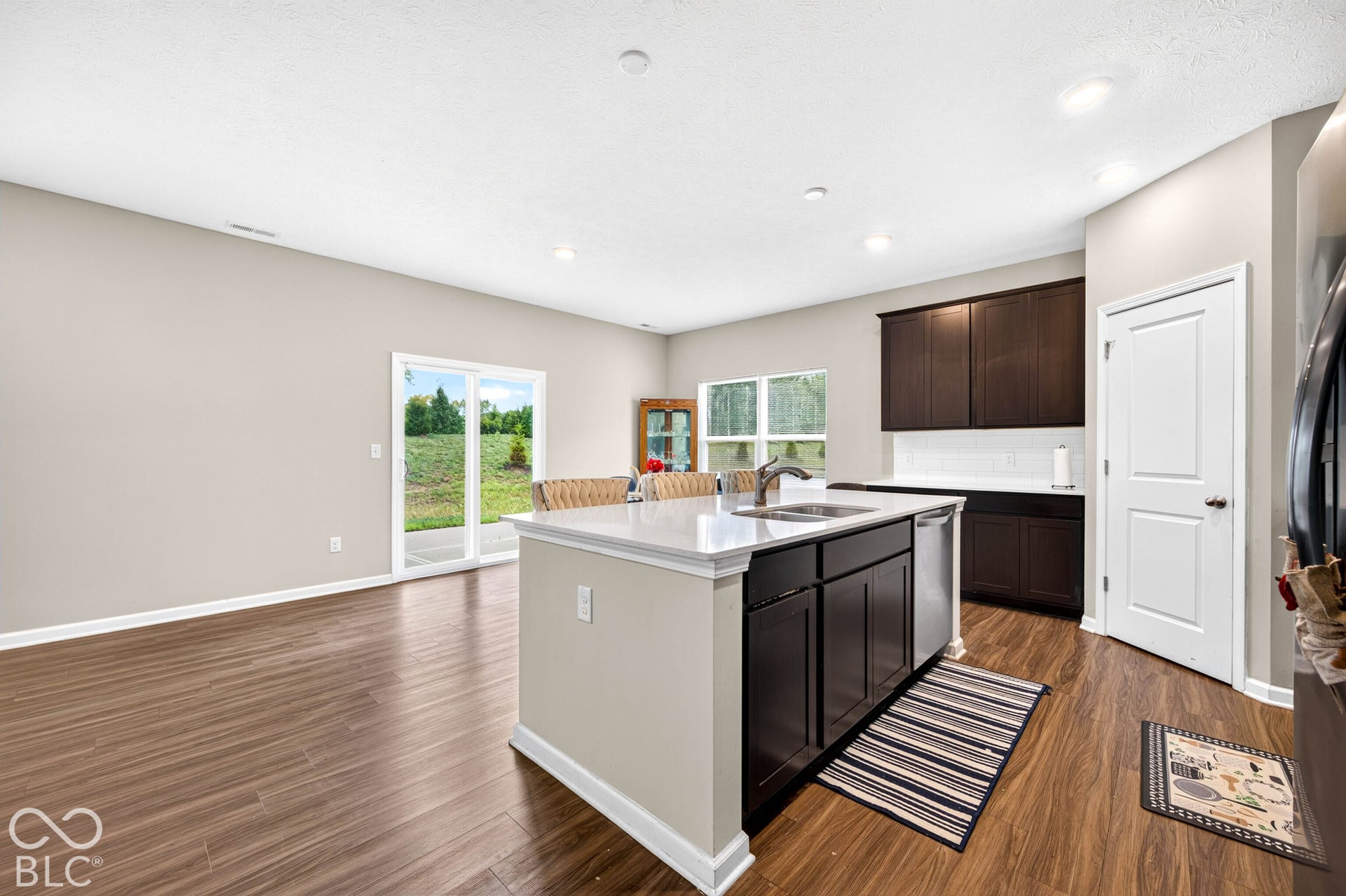 Kitchen featuring an island with a light-toned countertop, dark cabinetry, recessed lighting, and wood-finish flooring
