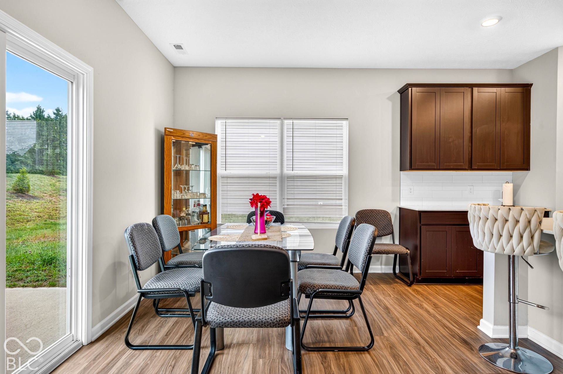 Wood-finish flooring, dark wood cabinetry, white tile backsplash, recessed lighting, and sliding glass door with exterior access
