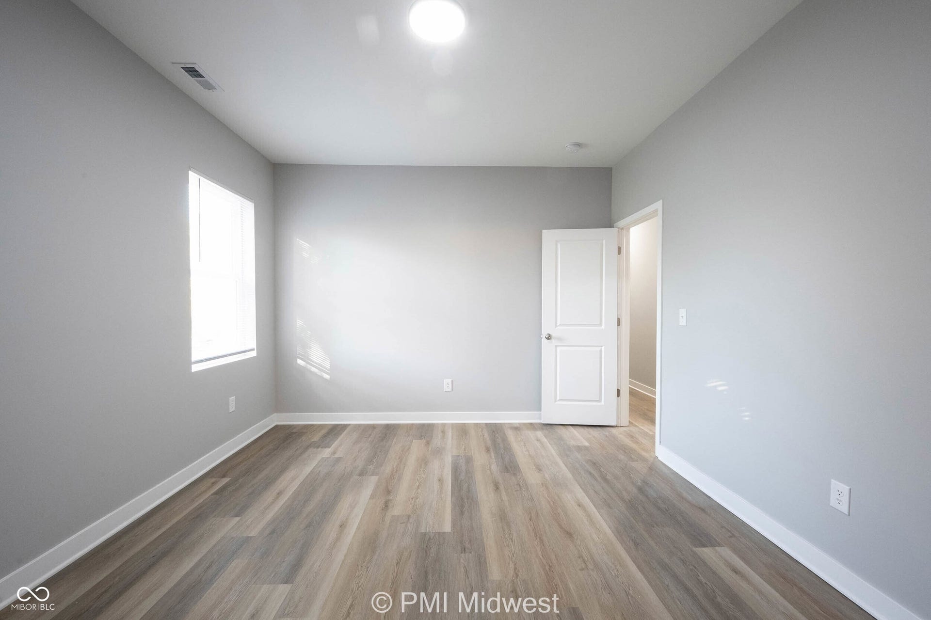 Room featuring wood-finish flooring, light gray wall paint, and white trim