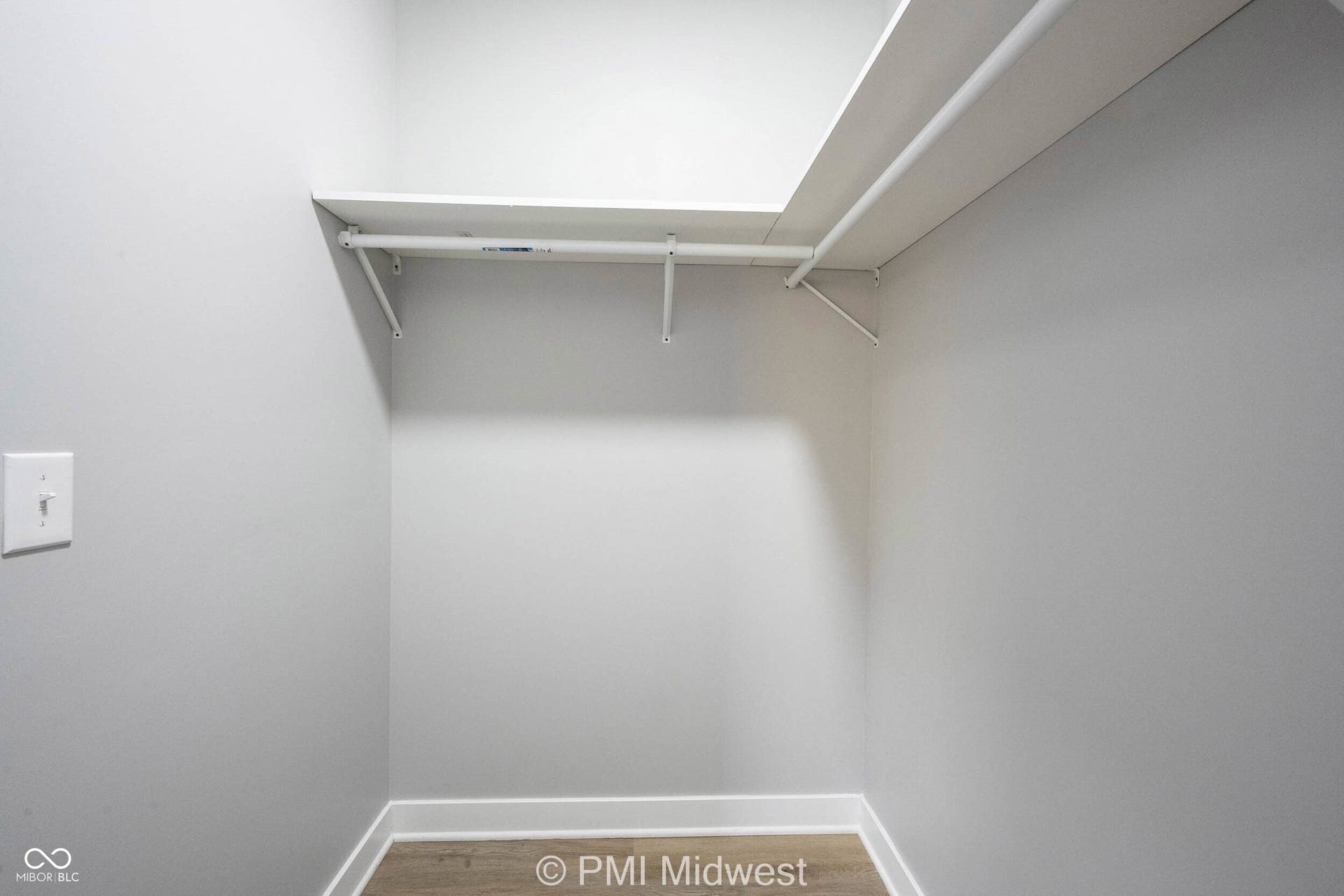 Recessed closet with light-toned walls, white shelving, and a hanging rod