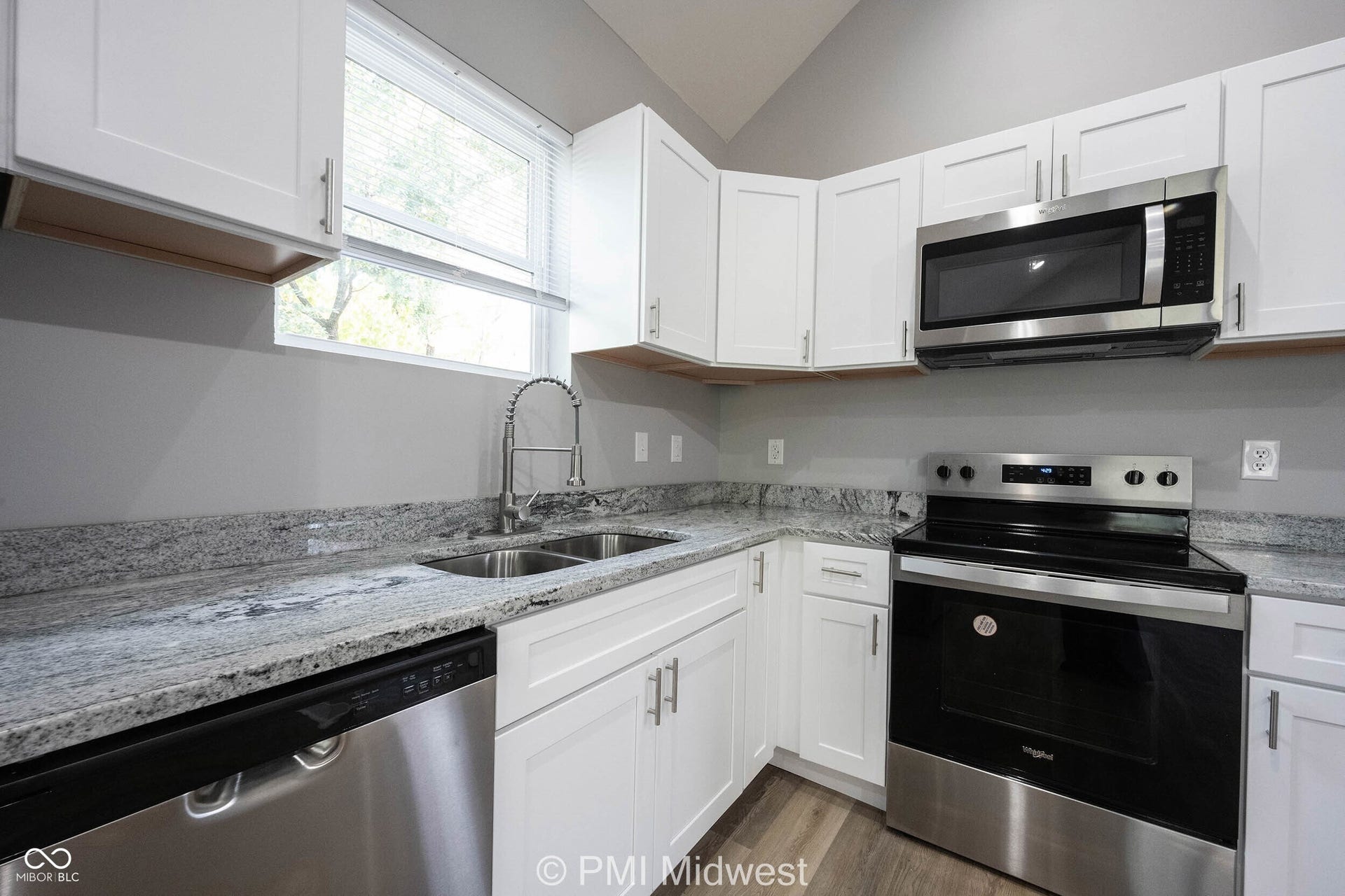 Kitchen featuring white cabinetry, grey countertops, stainless steel appliances, a double basin sink, and wood-finish flooring