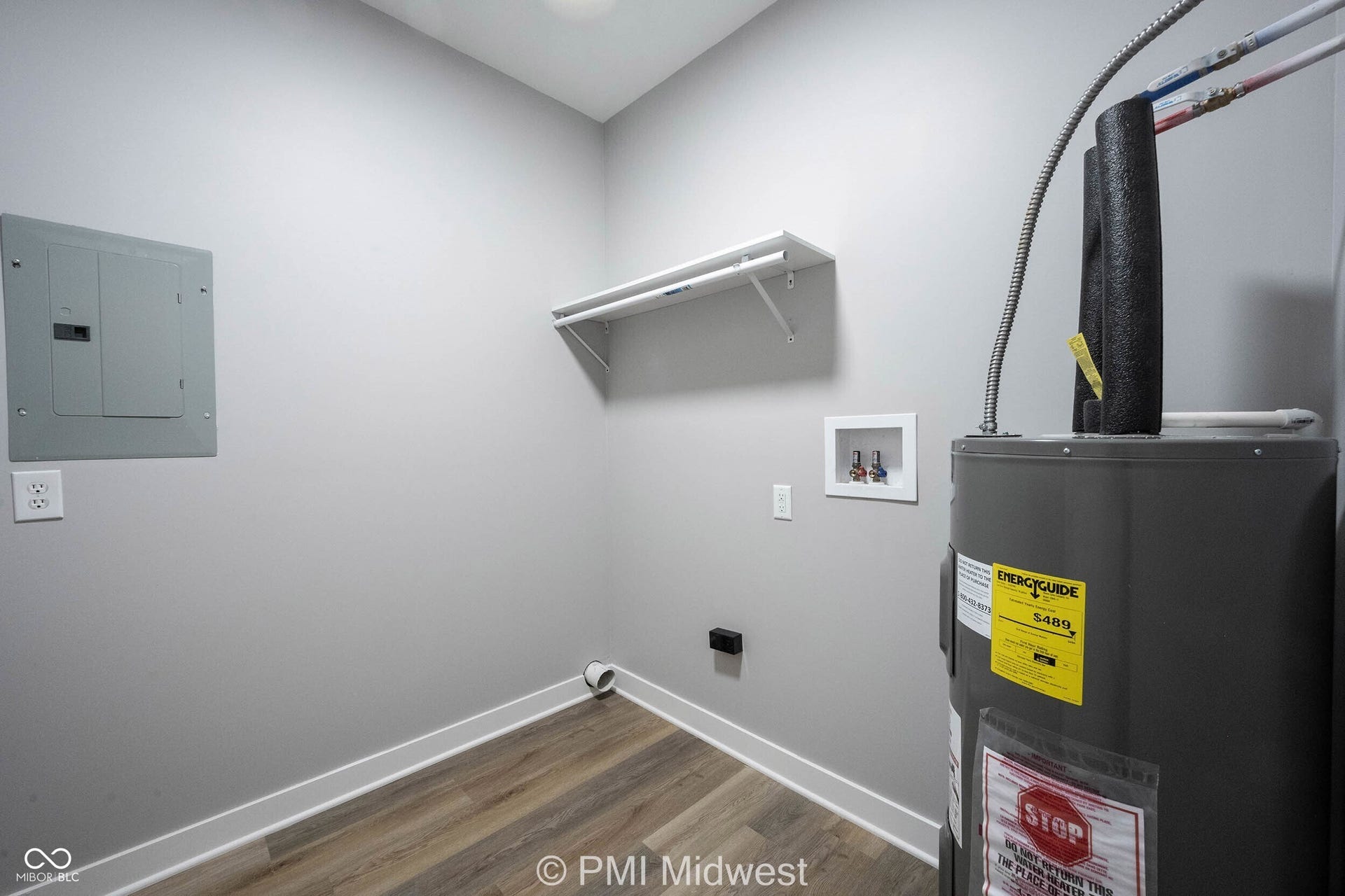 Utility room featuring wood-finish flooring, a water heater, electrical panel, and wall-mounted shelving