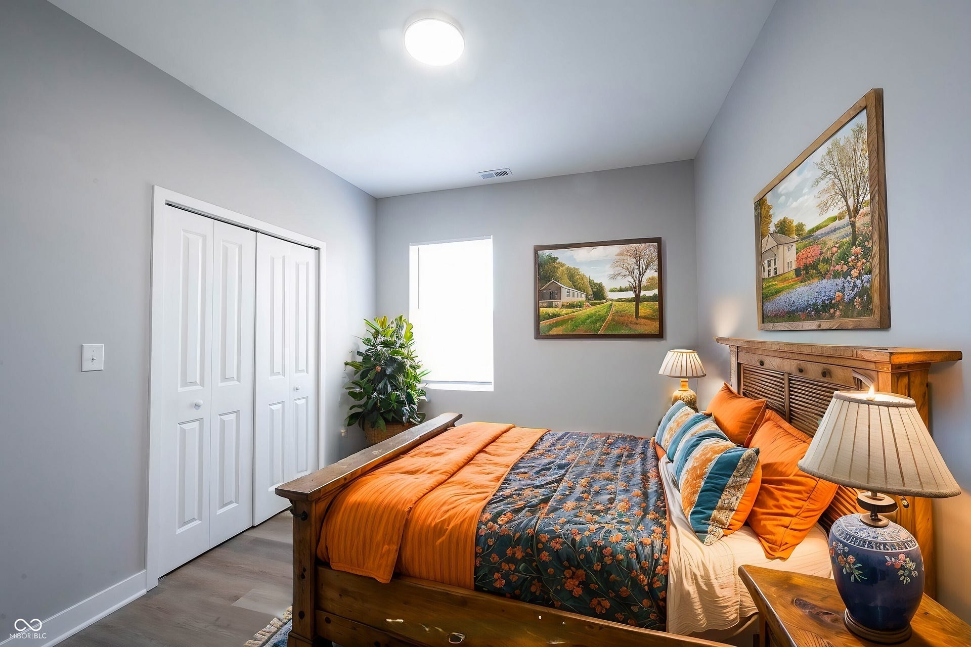 Bedroom featuring light gray walls, wood-finish flooring, a window providing natural light, a bi-fold closet, and a flush-mount ceiling light fixture